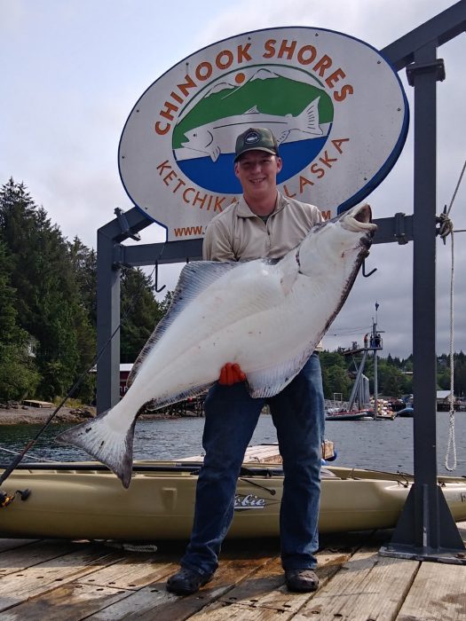 angler poses with halibut caught sport fishing out of kayak at Ketchikan fishing lodge