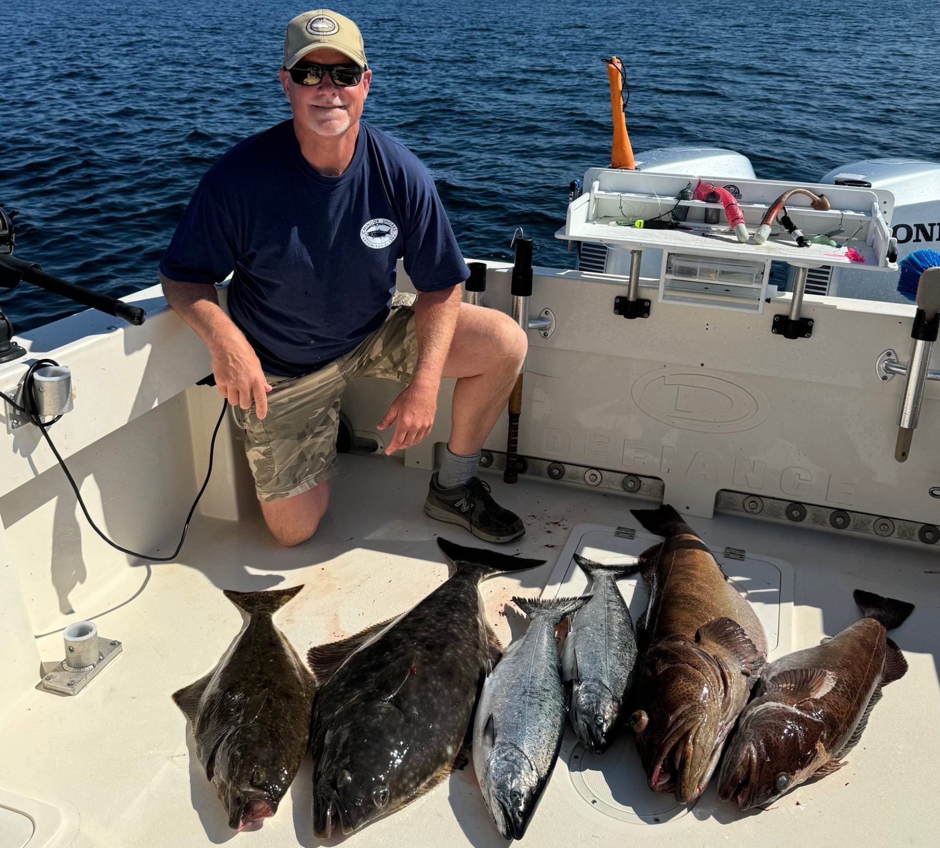 Charter captain poses with halibut, king salmon and lingcod caught sport fishing