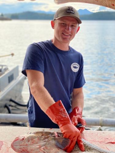 Fish Processing Dockhand fillets pacific cod at a sport fishing lodge in Ketchikan Alaska