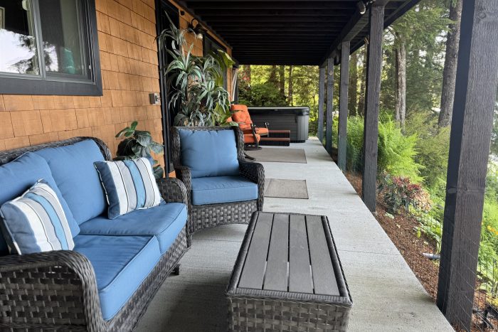 Spacious deck with furniture and private hot tub overlooking the water at fishing lodge in Ketchikan Alaska
