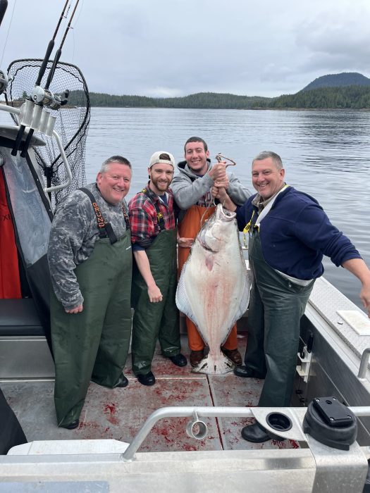 Group of fishermen pose in Silver Streak sport fishing boat with halibut caught at Ketchikan fishing lodge
