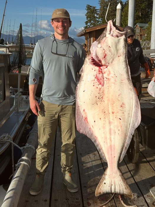 self-guided fisherman poses with trophy halibut caught at sport fishing lodge in Ketchikan Alaska